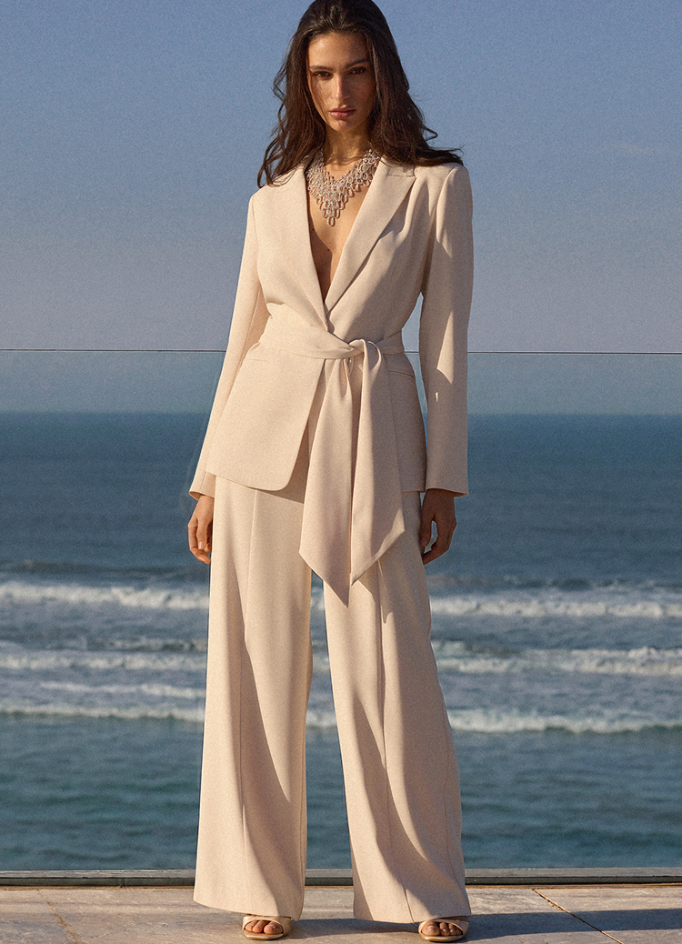 Презентація елегантного жіночого костюмного комплекту з приталеним піджаком і брюками з широкими штанинами, призначена для демонстрації посадки та стилю для формального або святкового вбрання.