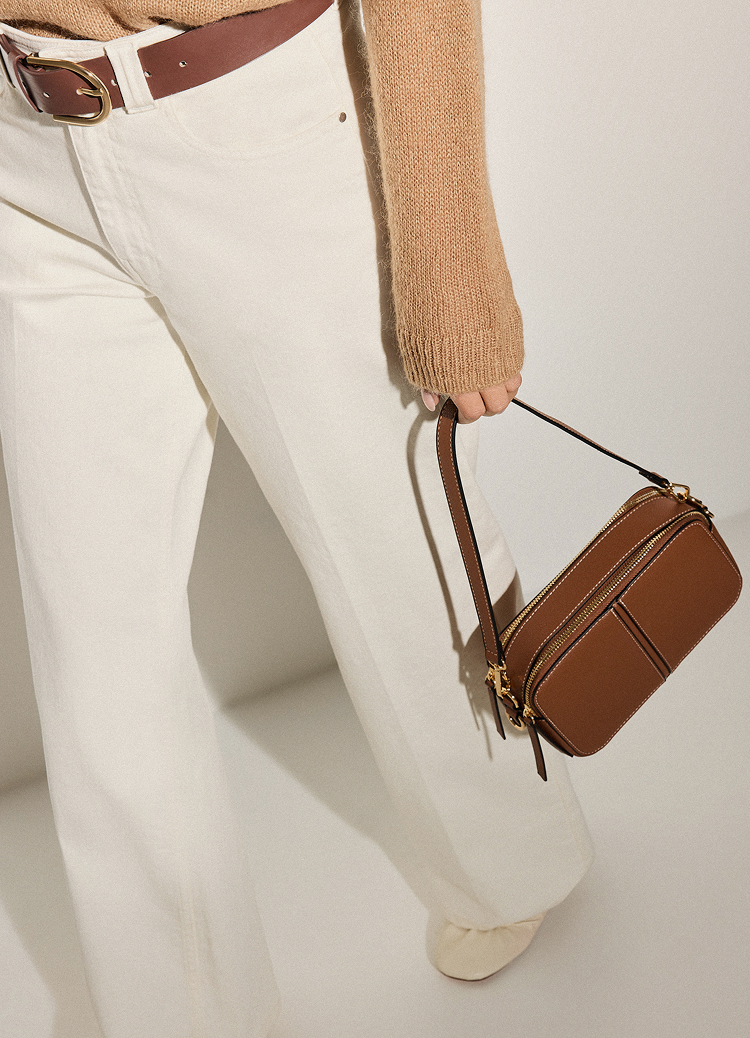 Pokazuje, jak mała torba na ramię uzupełnia casualowy strój, prezentując sposób noszenia i stylizacji dodatku na co dzień.