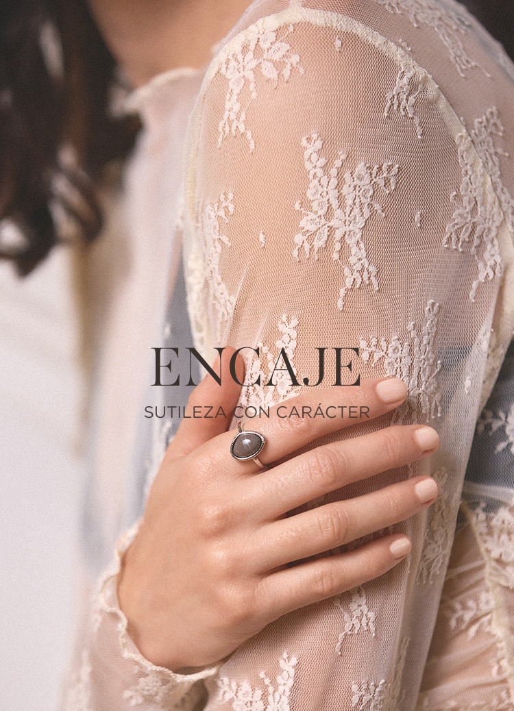 Detalle de manga de encaje transparente con diseño floral y anillo elegante, destacando delicadeza y estilo sofisticado.