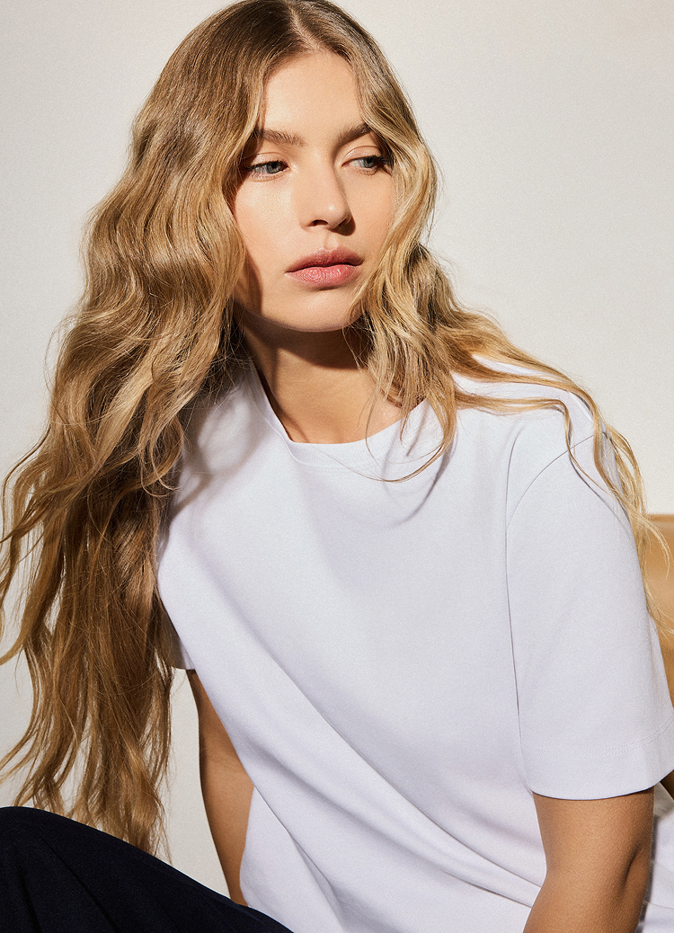 Prezentuje dopasowanie i układ krótkorękawowego topu podczas noszenia, pomagając kupującym ocenić styl, proporcje oraz to, jak układa się na sylwetce.