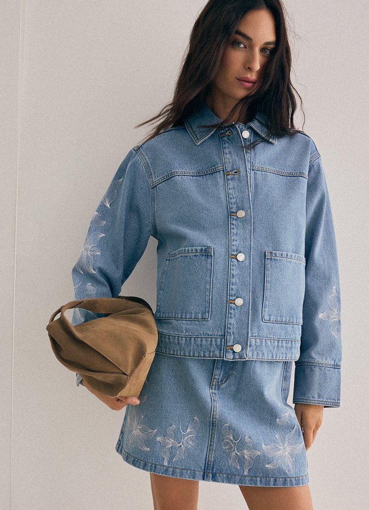 Presentation of a casual denim jacket and skirt set, demonstrating fit and overall styling for everyday wear, paired with a handbag.