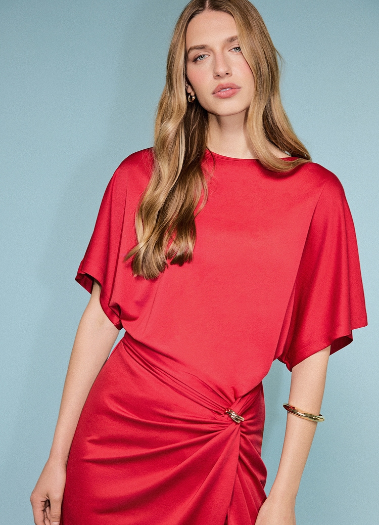 Kobieta w eleganckiej satynowej sukience midi z luźnymi rękawami i marszczonym detalem w talii, stylizowana z biżuterią na wieczorowy lub wyjątkowy look