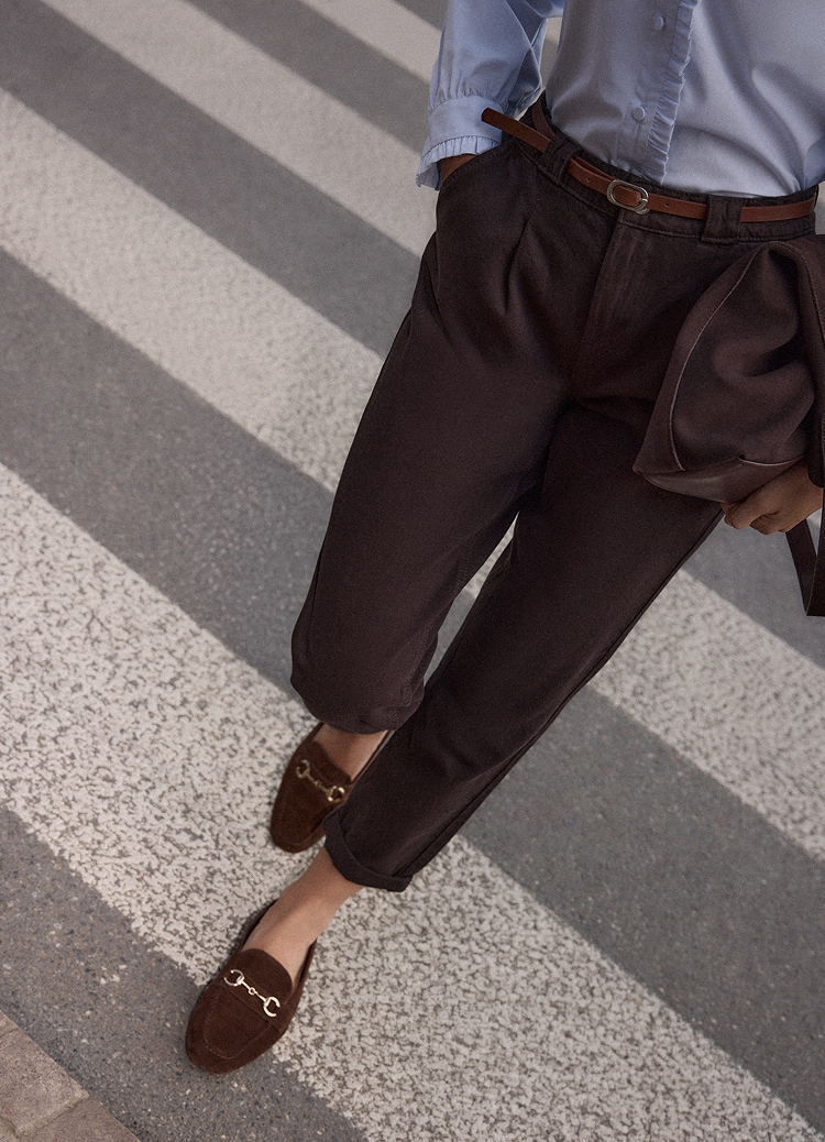 Elegancki damski strój z dopasowanymi spodniami, loafersami i torebką, stylizowany na smart casual na świeżym powietrzu